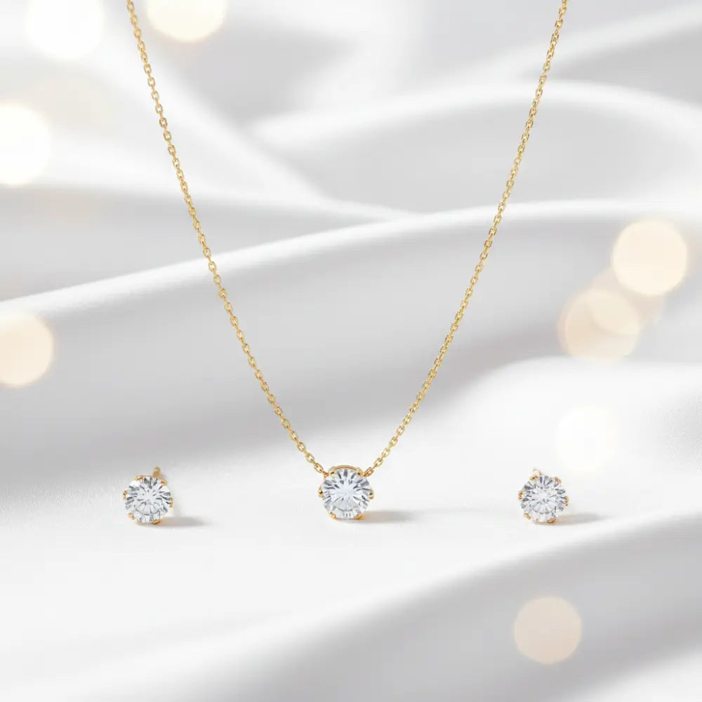 Gold necklace and earrings set on a soft white background