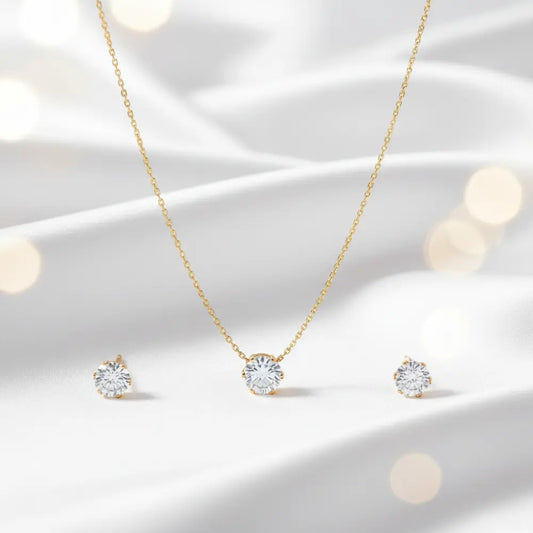Gold necklace and earrings set on a soft white background